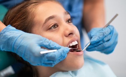 A young girl in close up as a dentist checks her teeth with instruments